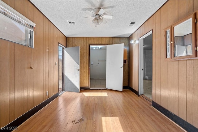 5101 Churchill Ave, Las Vegas, NV 89107 - unfurnished room with light wood-style floors, a ceiling fan, wooden walls, a textured ceiling, and baseboards