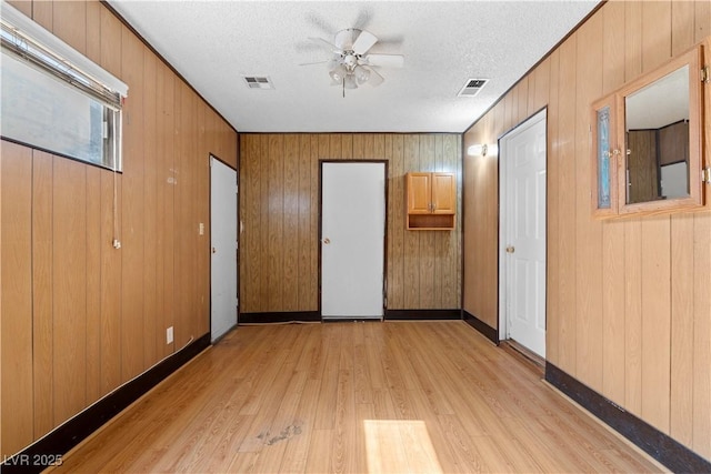 5101 Churchill Ave, Las Vegas, NV 89107 - unfurnished bedroom featuring light wood-style floors, wood walls, a textured ceiling, baseboards, and a ceiling fan