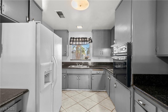 5101 Churchill Ave, Las Vegas, NV 89107 - kitchen featuring white refrigerator with ice dispenser, gray cabinets, stainless steel oven, light tile patterned flooring, and a sink