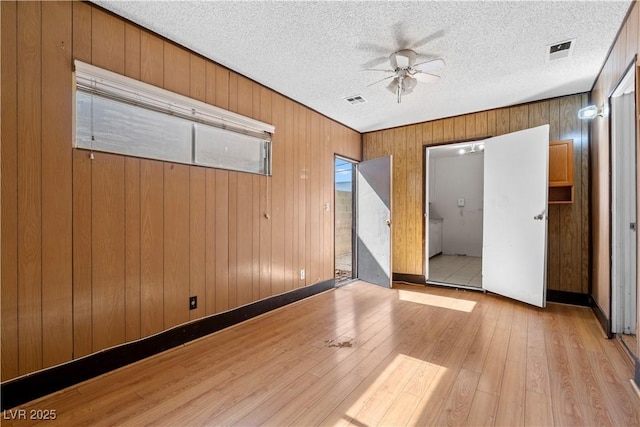 5101 Churchill Ave, Las Vegas, NV 89107 - unfurnished bedroom with light wood-style floors, wooden walls, access to exterior, a textured ceiling, and ceiling fan