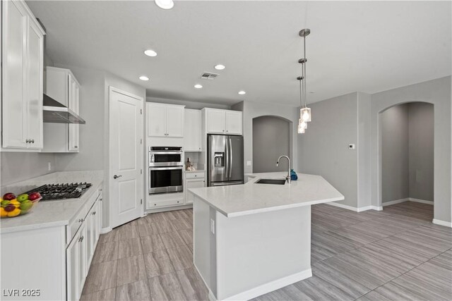 10416 Skye Arroyo Ave, Las Vegas, NV 89166 - kitchen featuring arched walkways, stainless steel appliances, a sink, recessed lighting, and white cabinets