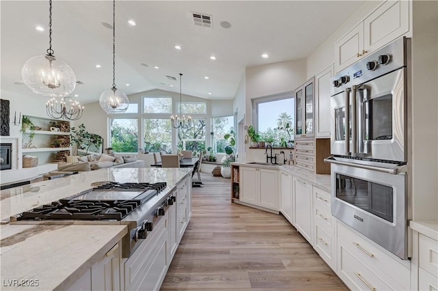 2345 Villandry Ct, Henderson, NV 89074 - kitchen featuring a chandelier, stainless steel appliances, light stone countertops, vaulted ceiling, and light wood finished floors