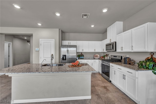 9876 Magnus Ct, Las Vegas, NV 89178 - kitchen with stainless steel appliances, a sink, a center island with sink, light stone counters, and white cabinetry