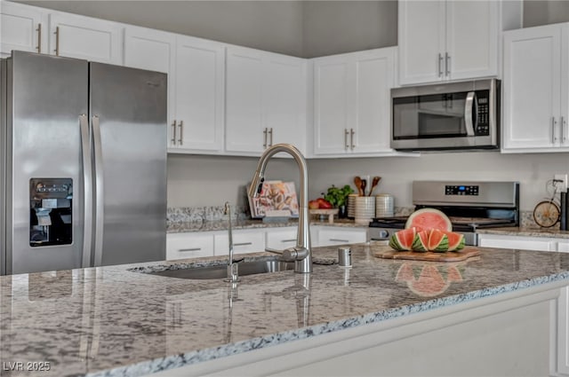 9876 Magnus Ct, Las Vegas, NV 89178 - kitchen with appliances with stainless steel finishes, white cabinetry, and light stone counters