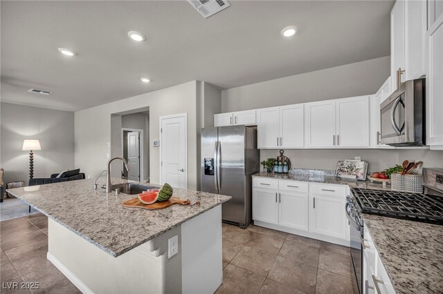 9876 Magnus Ct, Las Vegas, NV 89178 - kitchen with stainless steel appliances, a sink, light stone countertops, white cabinets, and a center island with sink