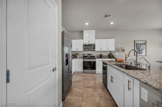 9876 Magnus Ct, Las Vegas, NV 89178 - kitchen featuring appliances with stainless steel finishes, a sink, light stone countertops, white cabinets, and recessed lighting