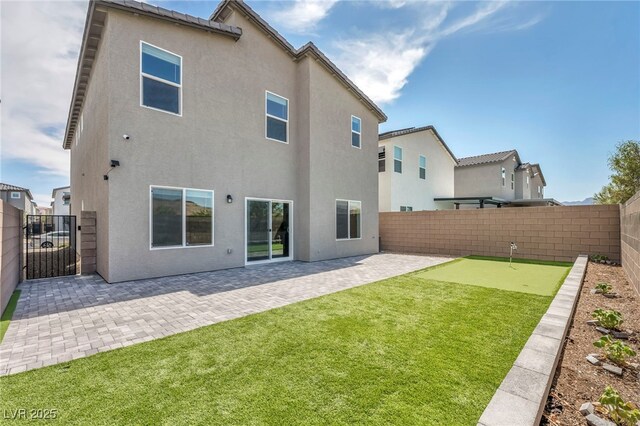 9876 Magnus Ct, Las Vegas, NV 89178 - back of property with an area to practice putting, stucco siding, and a patio