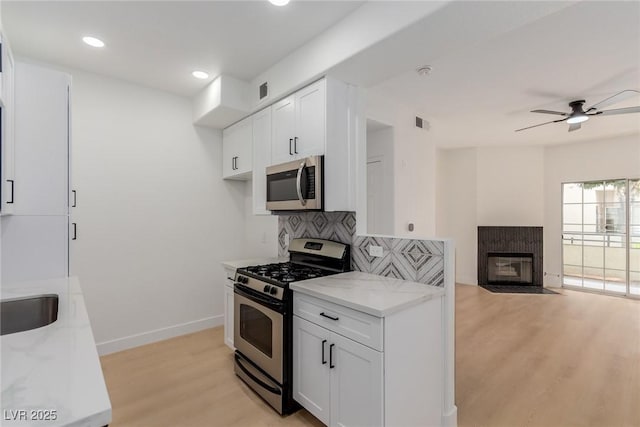 3318 N Decatur Blvd Unit 1020, Las Vegas, NV 89130 - kitchen with appliances with stainless steel finishes, light stone countertops, decorative backsplash, light wood-style flooring, and white cabinets