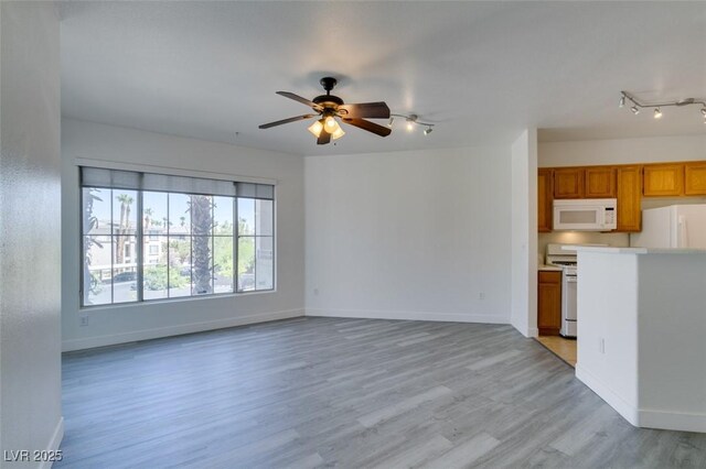 7151 S Durango Dr Unit 211, Las Vegas, NV 89113 - unfurnished living room featuring rail lighting, light wood-type flooring, a ceiling fan, and baseboards