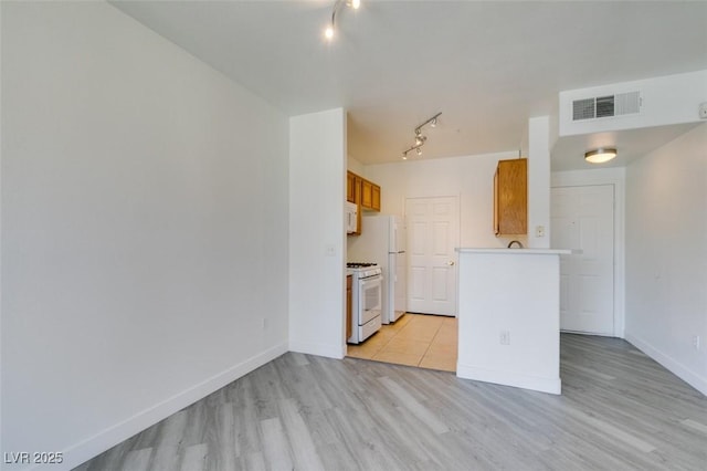 7151 S Durango Dr Unit 211, Las Vegas, NV 89113 - kitchen with white appliances, rail lighting, light wood-style floors, baseboards, and light countertops