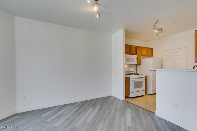7151 S Durango Dr Unit 211, Las Vegas, NV 89113 - kitchen featuring white appliances, rail lighting, light wood-style floors, brown cabinetry, and light countertops