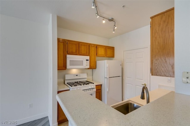 7151 S Durango Dr Unit 211, Las Vegas, NV 89113 - kitchen with white appliances, a sink, brown cabinets, baseboards, and light stone countertops