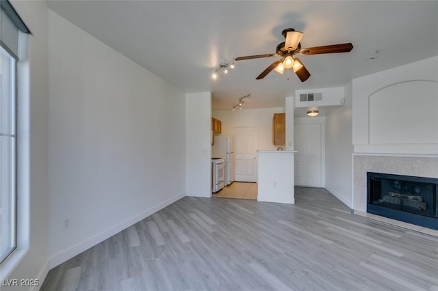 7151 S Durango Dr Unit 211, Las Vegas, NV 89113 - unfurnished living room featuring a ceiling fan, light wood-style flooring, baseboards, and a tile fireplace