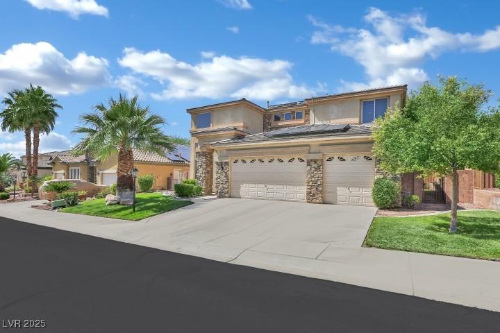 2382 Sunburst View St, Henderson, NV 89052 - view of front of home featuring concrete driveway, roof mounted solar panels, stucco siding, stone siding, and an attached garage