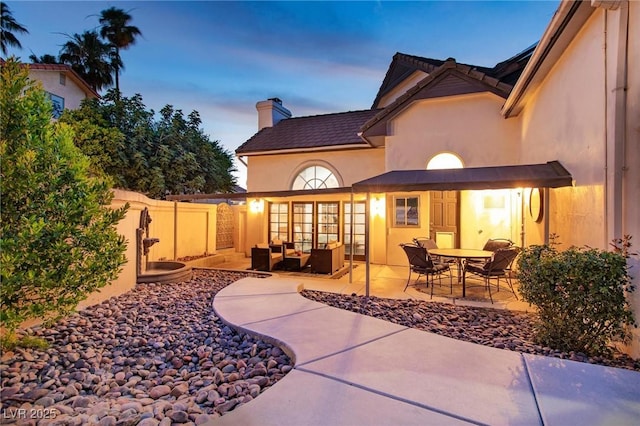 15 Pheasant Ridge Dr, Henderson, NV 89014 - back of property at dusk with an outdoor living space, a chimney, a patio, and stucco siding