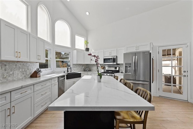 15 Pheasant Ridge Dr, Henderson, NV 89014 - kitchen featuring stainless steel appliances, high vaulted ceiling, a sink, a breakfast bar area, and decorative backsplash
