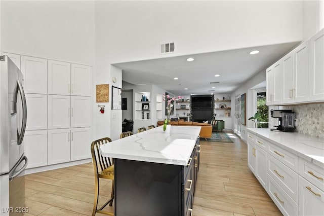 15 Pheasant Ridge Dr, Henderson, NV 89014 - kitchen with stainless steel refrigerator with ice dispenser, white cabinetry, light stone countertops, light wood-type flooring, and recessed lighting
