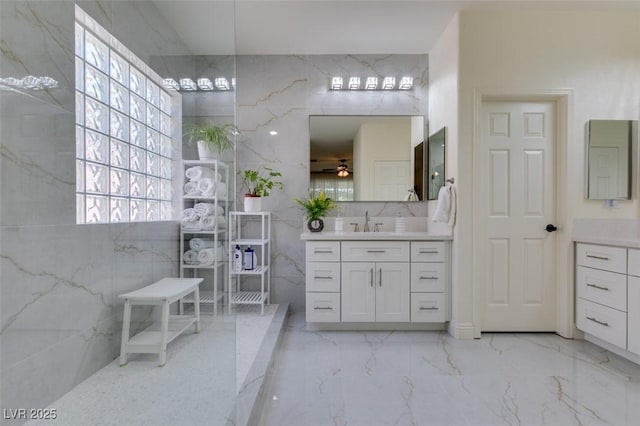 8221 Bay Dunes St, Las Vegas, NV 89131 - full bathroom with tile walls, vanity, marble tiled floors, ceiling fan, and a marble finish shower