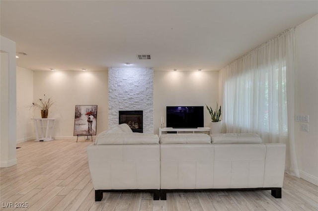 8221 Bay Dunes St, Las Vegas, NV 89131 - living area featuring a stone fireplace, light wood-style flooring, and baseboards