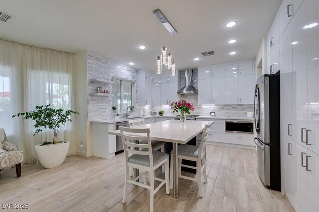 8221 Bay Dunes St, Las Vegas, NV 89131 - kitchen featuring stainless steel appliances, wall chimney exhaust hood, modern cabinets, a kitchen bar, and white cabinets