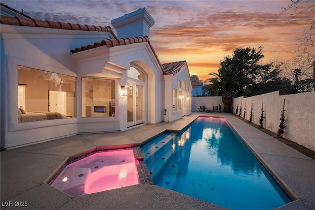 8104 Bay Harbor Dr, Las Vegas, NV 89128 - pool at dusk featuring a patio area, a fenced backyard, and a pool with connected hot tub