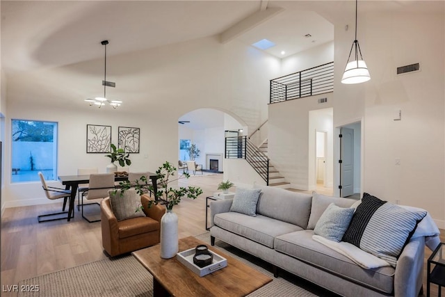 8104 Bay Harbor Dr, Las Vegas, NV 89128 - living room with arched walkways, light wood finished floors, stairs, a towering ceiling, and beam ceiling