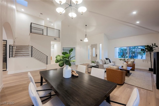 8104 Bay Harbor Dr, Las Vegas, NV 89128 - dining space featuring light wood-type flooring, arched walkways, stairway, a chandelier, and high vaulted ceiling