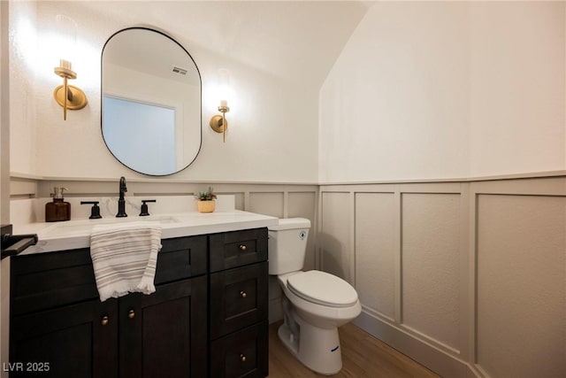 8104 Bay Harbor Dr, Las Vegas, NV 89128 - bathroom featuring toilet, vanity, wood finished floors, a decorative wall, and a wainscoted wall