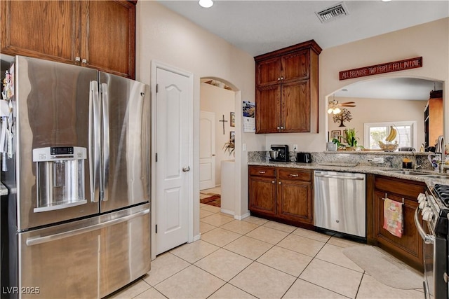 805 Palmero Way, Boulder City, NV 89005 - kitchen with stainless steel appliances, a sink, arched walkways, light tile patterned floors, and light stone countertops