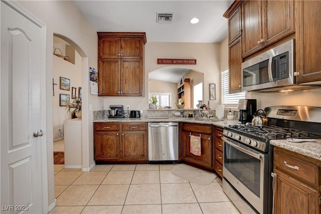 805 Palmero Way, Boulder City, NV 89005 - kitchen with appliances with stainless steel finishes, light tile patterned floors, light stone countertops, arched walkways, and brown cabinets