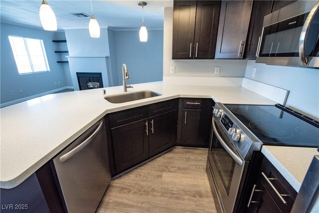 8600 W Charleston Blvd Unit 2068, Las Vegas, NV 89117 - kitchen with appliances with stainless steel finishes, a sink, light wood-style floors, a fireplace, and light countertops