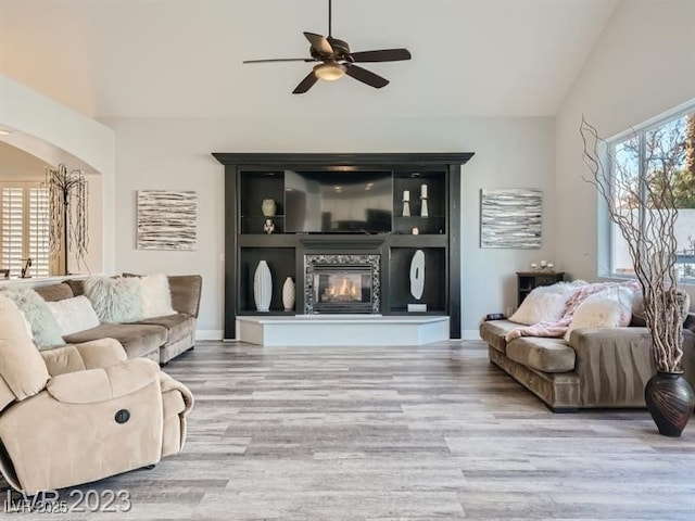 9718 Camino Capistrano Ln, Las Vegas, NV 89147 - living area with arched walkways, ceiling fan, wood finished floors, a glass covered fireplace, and lofted ceiling