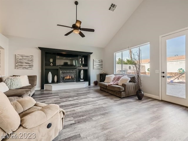 9718 Camino Capistrano Ln, Las Vegas, NV 89147 - living room with high vaulted ceiling, wood finished floors, a ceiling fan, baseboards, and a glass covered fireplace