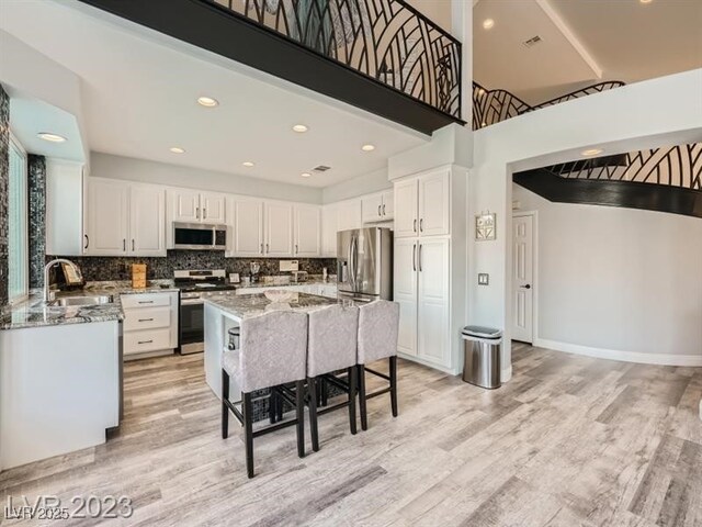 9718 Camino Capistrano Ln, Las Vegas, NV 89147 - kitchen with stainless steel appliances, light stone countertops, white cabinetry, and recessed lighting