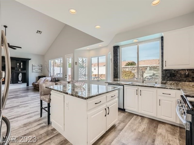 9718 Camino Capistrano Ln, Las Vegas, NV 89147 - kitchen with stainless steel appliances, a sink, dark stone countertops, a center island, and recessed lighting