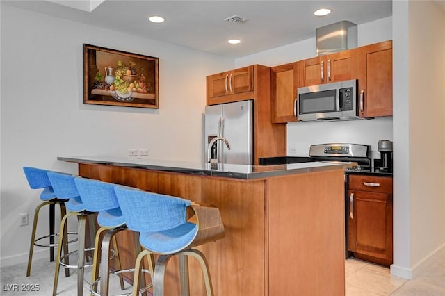 4525 Dean Martin Dr Unit 901, Las Vegas, NV 89103 - kitchen featuring appliances with stainless steel finishes, a breakfast bar, dark countertops, baseboards, and brown cabinets
