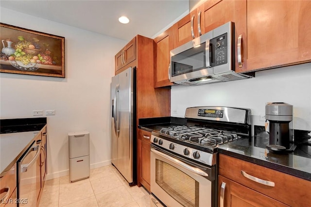 4525 Dean Martin Dr Unit 901, Las Vegas, NV 89103 - kitchen with stainless steel appliances, brown cabinets, light tile patterned floors, baseboards, and dark stone counters