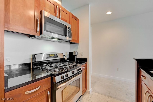 4525 Dean Martin Dr Unit 901, Las Vegas, NV 89103 - kitchen featuring stainless steel appliances, light colored carpet, brown cabinetry, light tile patterned flooring, and dark stone countertops