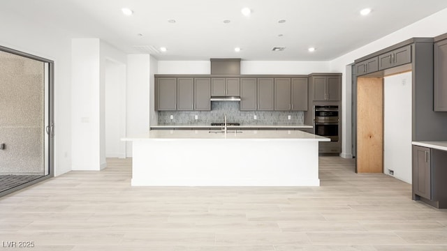 362 Tigullio Ave, Henderson, NV 89011 - kitchen with stainless steel double oven, a kitchen island with sink, light countertops, gray cabinets, and recessed lighting