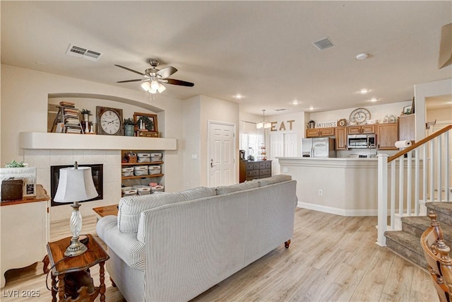 67 Dow Jones St Unit 2, Henderson, NV 89074 - living room featuring light wood-style flooring, ceiling fan, stairway, a tiled fireplace, and recessed lighting
