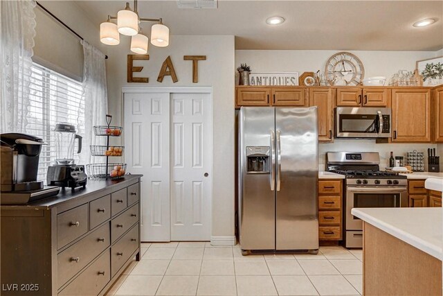 67 Dow Jones St Unit 2, Henderson, NV 89074 - kitchen with stainless steel appliances, light tile patterned floors, brown cabinets, and pendant lighting