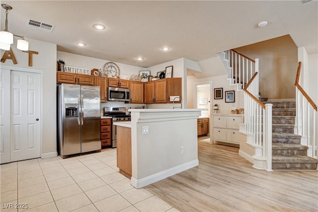 67 Dow Jones St Unit 2, Henderson, NV 89074 - kitchen featuring stainless steel appliances, light countertops, brown cabinets, light wood-style floors, and decorative light fixtures
