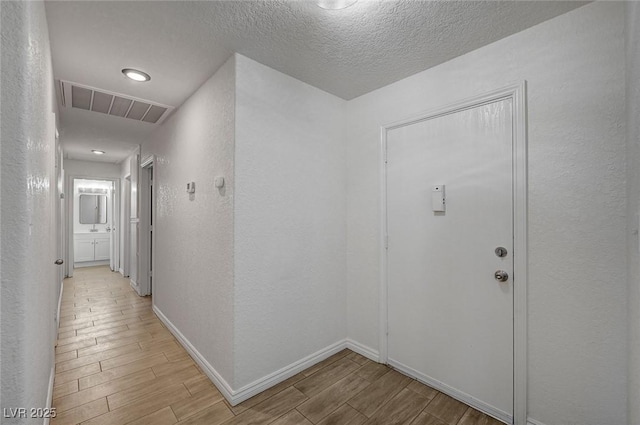 4496 Skyview Dr, Las Vegas, NV 89104 - hall featuring light wood-style floors, a textured wall, baseboards, and a textured ceiling
