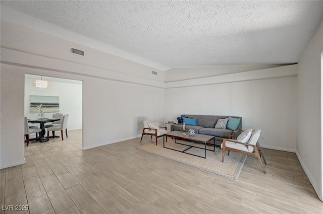 4496 Skyview Dr, Las Vegas, NV 89104 - living room featuring a textured ceiling, vaulted ceiling, light wood-type flooring, and baseboards