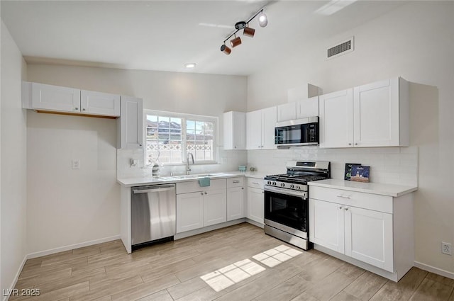 4496 Skyview Dr, Las Vegas, NV 89104 - kitchen featuring appliances with stainless steel finishes, a sink, decorative backsplash, white cabinetry, and light wood-style floors