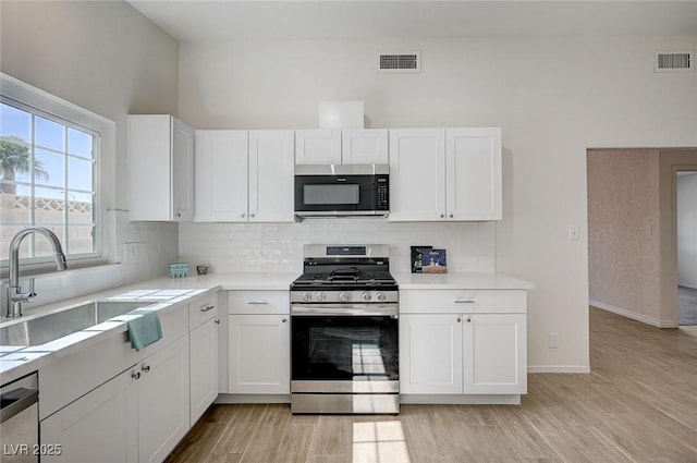 4496 Skyview Dr, Las Vegas, NV 89104 - kitchen with appliances with stainless steel finishes, a sink, white cabinets, light countertops, and tasteful backsplash