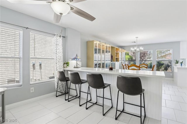 3966 Crystal Trip Ct, Las Vegas, NV 89129 - kitchen featuring a chandelier, light countertops, a ceiling fan, and a kitchen breakfast bar