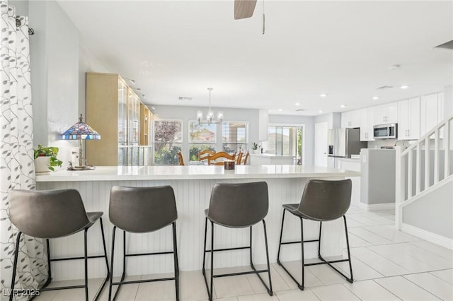 3966 Crystal Trip Ct, Las Vegas, NV 89129 - kitchen featuring stainless steel appliances, light countertops, white cabinetry, a peninsula, and a kitchen bar