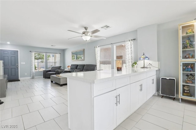 3966 Crystal Trip Ct, Las Vegas, NV 89129 - kitchen with a peninsula, ceiling fan, light countertops, light tile patterned floors, and white cabinets