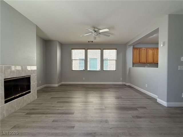 258 Bella Matese Ave, Las Vegas, NV 89183 - unfurnished living room featuring ceiling fan, baseboards, a fireplace, and light wood-style floors